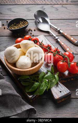Salade Caprese, ingrédients pour la cuisine. Planche de bois à découper avec des ingrédients traditionnels de préparation caprese : mozzarella, toma Banque D'Images