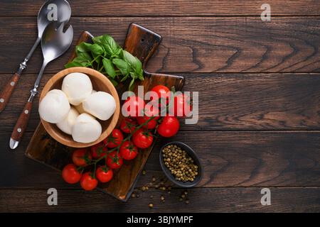 Salade Caprese, ingrédients pour la cuisine. Planche de bois à découper avec des ingrédients traditionnels de préparation caprese : mozzarella, toma Banque D'Images