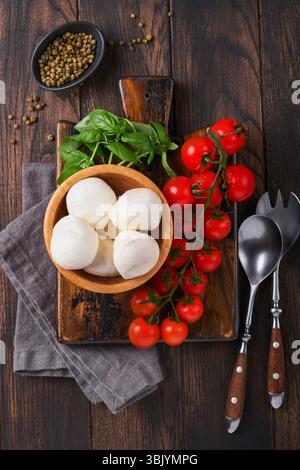 Salade Caprese, ingrédients pour la cuisine. Planche de bois à découper avec des ingrédients traditionnels de préparation caprese : mozzarella, toma Banque D'Images
