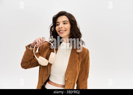 Jeune femme élégante pose en toute confiance avec des écouteurs dans un cadre de studio. Banque D'Images