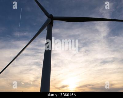 Vue aérienne d'une éolienne sur un champ agricole au coucher du soleil. Gros plan des lames. Banque D'Images