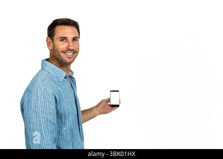 Homme tenant le smartphone affichant un écran blanc vierge contre fond blanc de studio, espace de copie Banque D'Images