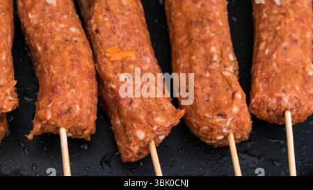Gros plan de brochettes de viande Kofta crue cuisant sur le gril Banque D'Images