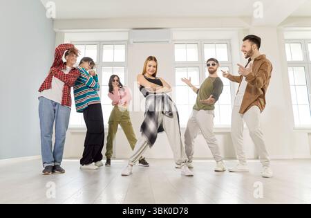 Groupe de danse de jeunes gens sympas dansant activement à l'intérieur, se déplaçant posant dans un studio moderne lumineux Banque D'Images