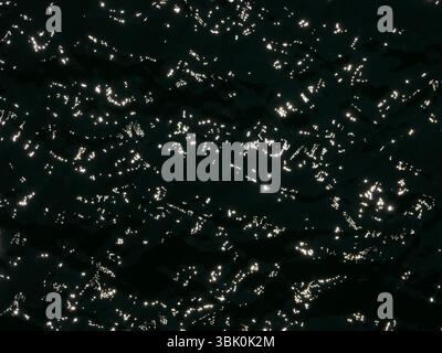 Vue de dessus à contraste élevé de la surface de l'eau. Soleil éblouissant sur l'eau édition noir et blanc. Texture abstraite de fond d'écran. Banque D'Images