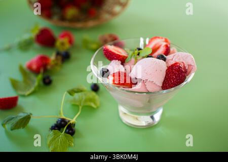 Crème glacée crémeuse avec des baies sur un fond vert. Banque D'Images