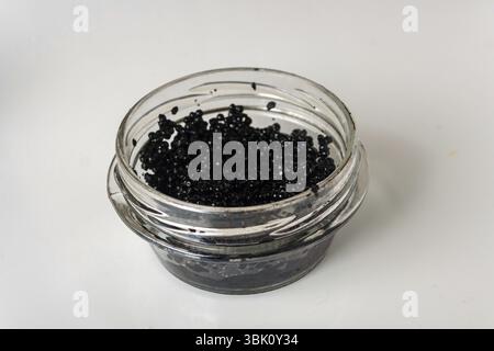 Caviar noir dans un bocal en verre sur verre blanc Banque D'Images