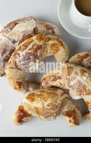 Une tasse d'espresso, des croissants dans du sucre en poudre sur une table blanche Banque D'Images