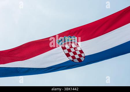 Le drapeau croate agitant contre un ciel bleu clair. Le drapeau présente des bandes horizontales rouges, blanches et bleues avec un bouclier à damier portant le Banque D'Images