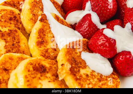 Les crêpes dorées sont servies avec des fraises fraîches recouvertes de crème fouettée, créant une délicieuse tartinade parfaite pour un matin ensoleillé. Banque D'Images