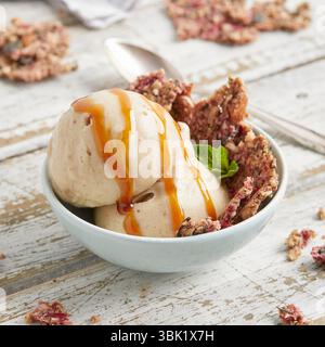 Des boules de crème à la banane agrémentée de sauce caramel et de chapelure de biscuit – un dessert glacé végétalien, sucré et crémeux, parfait pour l’été. Banque D'Images