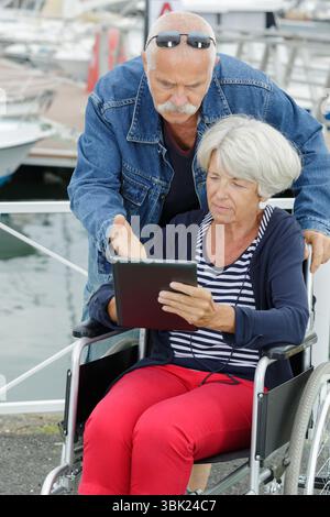 homme et femme âgée en fauteuil roulant à l'aide d'une tablette Banque D'Images