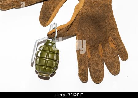 Gants de protection de type militaire tenant une grenade à main factice en plastique. EQUIPEMENT d'entraînement ou de simulation. Usage éditorial exclusif. Banque D'Images
