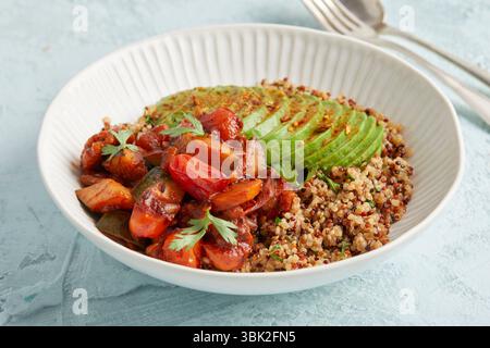 Bol de quinoa sain avec avocat, noix et tomates – un déjeuner ou un dîner coloré à base de plantes. Banque D'Images