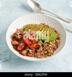 Bol de quinoa sain avec avocat, noix et tomates – un déjeuner ou un dîner coloré à base de plantes. Banque D'Images