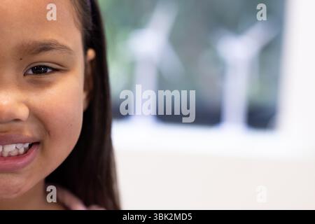 Fille souriante en classe avec des éoliennes en arrière-plan, se sentant heureuse, espace de copie, à l'école Banque D'Images