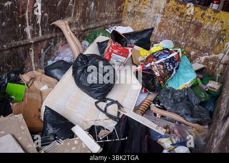 Les jambes et un bras d'un mannequin de vente au détail dépassent d'autres déchets de décharge dans une benne au centre de déchets ménagers et de recyclage de l'arrondissement de Wandsworth sur Smugglers Way, le 17 juin 2025, à Londres, en Angleterre. Les déchets mis en décharge sont l'élimination de déchets qui ne peuvent pas être réutilisés, recyclés ou valorisés, dans ou sur le sol. Banque D'Images