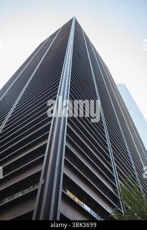 Le gratte-ciel de bureau moderne s'élève dans un design plat, mettant en valeur les persiennes en métal et les fenêtres en verre Banque D'Images