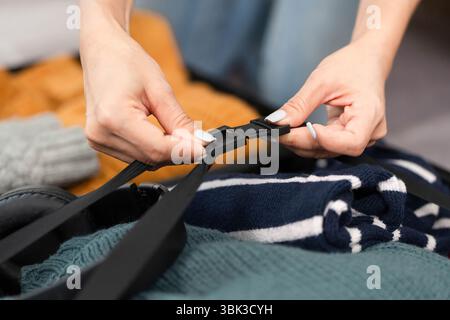 Réglage des sangles à bagages. Une jeune femme attachant des sangles sur sa valise emballée. Banque D'Images