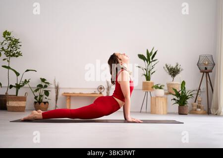 Jeune femme pratiquant urdhva mukha svanasana yoga pose à la maison Banque D'Images