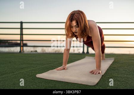 Une jeune femme athlétique en vêtements de sport prend une pause rafraîchissante, buvant une boisson dans une canette tout en étant assise à l'extérieur après une séance d'entraînement. Un concept de hyd Banque D'Images