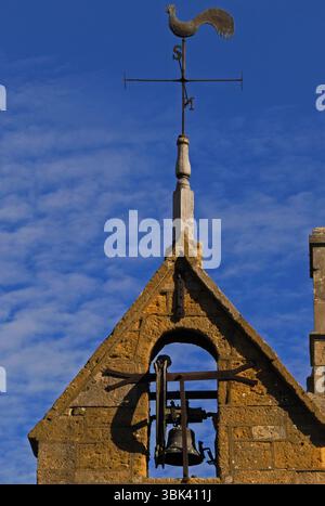 Les couronnes de coq en plomb sont une girouette au-dessus du pignon en pierre Cotswold couleur miel de la tour de couvre-feu à Moreton-in-Marsh, Gloucestershire, Angleterre, Royaume-Uni. Tour date probablement des années 1500 et est très rare survie architecturale. Il a une ancienne cellule de prison ou de prison à sa base, une horloge de 1648 et la cloche du couvre-feu de 1633, qui a été sonné tous les soirs jusqu’en 1860 pour avertir les résidents de « couvrir le feu » la nuit – essentiel dans un endroit où la plupart des maisons avaient des toits de chaume hautement inflammables. La tour se trouve à la jonction d'Oxford Street et High Street. Banque D'Images