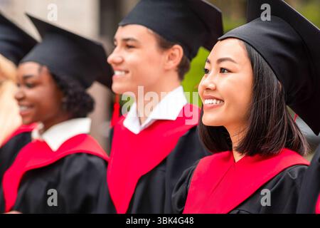 Groupe multiracial de diplômés ayant la cérémonie de remise des diplômes, clôture Banque D'Images