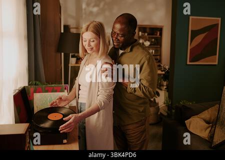 Couple senior diversifié appréciant un moment romantique écoutant de la musique Banque D'Images