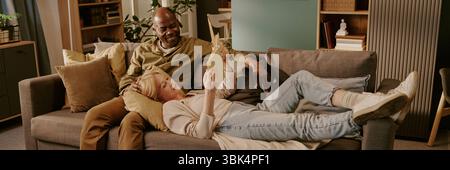 Femme caucasienne senior couchée sur canapé avec homme noir senior partageant un moment tendre Banque D'Images