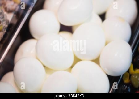 Plusieurs œufs durs pelés sont empilés sur un plateau de service noir dans un buffet plat Banque D'Images