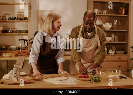 Femme caucasienne senior et homme noir senior préparant la nourriture ensemble dans la cuisine Banque D'Images