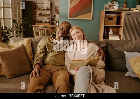 Couple multiethnique senior assis ensemble sur Sofa Sharing moment romantique Banque D'Images