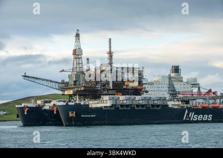 L'énorme navire pionnier Spirit arrive à Dales Voe dans les Shetland, livrant la plate-forme Ninian Northern au sommet pour le déclassement, marquant un m Banque D'Images