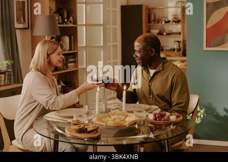 Femme caucasienne senior et homme noir senior appréciant un dîner romantique ensemble Banque D'Images