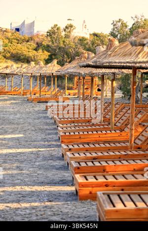 Chaises de lit et parasols de paille se sont entassés sur une plage à Tinos, le groupe d'îles des Cyclades, Grèce. Prise juin 2025 été Banque D'Images