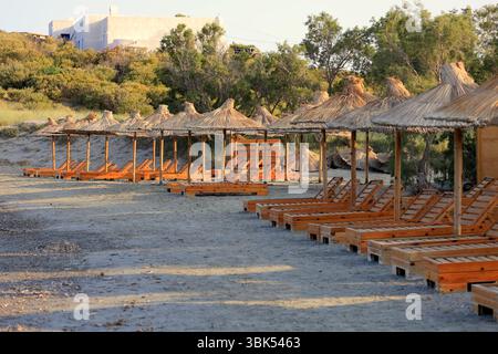 Chaises de lit et parasols de paille se sont entassés sur une plage à Tinos, le groupe d'îles des Cyclades, Grèce. Prise juin 2025 été Banque D'Images
