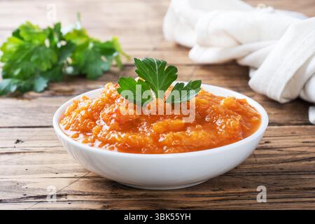 Caviar fait maison à partir de tomates courgettes et d'oignons dans une plaque en céramique sur un fond en bois. Conserves de production maison, conserves de légumes cuits en conserves Banque D'Images