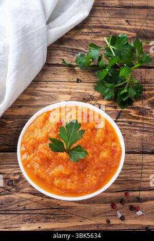 Caviar fait maison à partir de tomates courgettes et d'oignons dans une plaque en céramique sur un fond en bois. Conserves de production maison, conserves de légumes cuits en conserves Banque D'Images