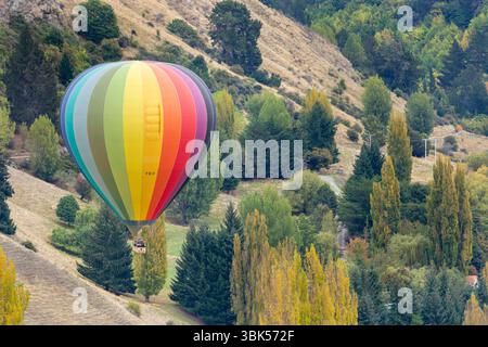 Une montgolfière volant bas au-dessus des arbres près de Queenstown, Otago, Nouvelle-Zélande Banque D'Images
