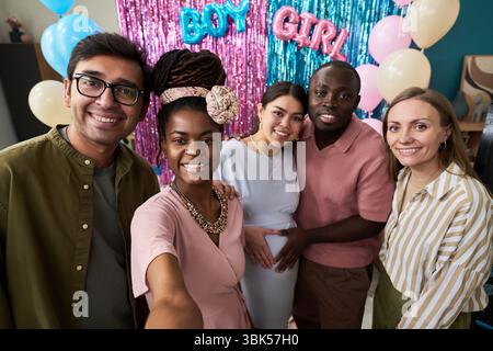 Groupe diversifié de jeunes adultes et de personnes d'âge moyen souriant et posant pour selfie à la fête de révélation du genre Banque D'Images