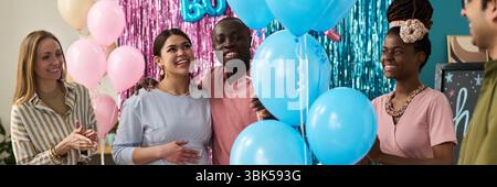 Groupe de jeunes amis multiethniques adultes célébrant la fête de révélation de genre, souriant et interagissant Banque D'Images