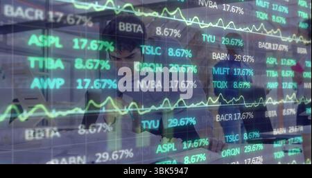 Analystes collaborateurs analysant des graphiques, des tickers sur ordinateur portable, tablette dans le bureau avec fenêtres, superposition Banque D'Images