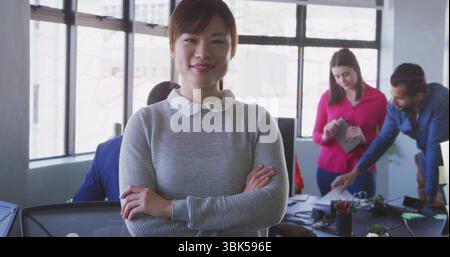 Collaboration de cinq professionnels examinant des documents dans un bureau lumineux, avec ordinateur portable et moniteur Banque D'Images