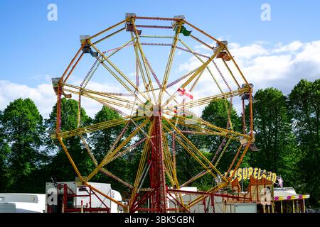 Un tour coloré de foire funfair avec une grande roue sous un ciel bleu à Saffron Walden, Essex, Royaume-Uni. Banque D'Images