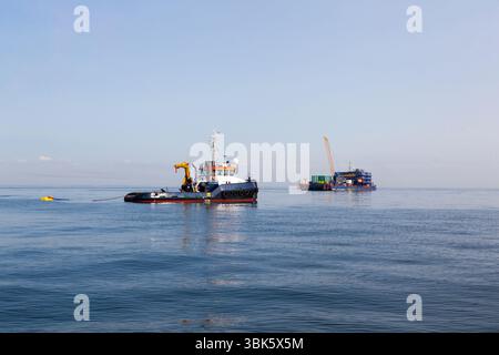 Grue flottante et remorqueur en pleine mer. Banque D'Images