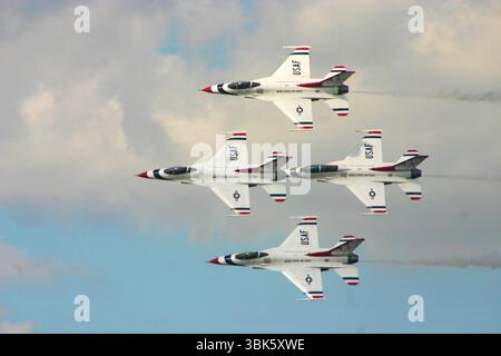 Les Thunderbirds de l'US Air Force volent en formation de précision lors d'un spectacle aérien, silhouettés contre un ciel nuageux. Banque D'Images