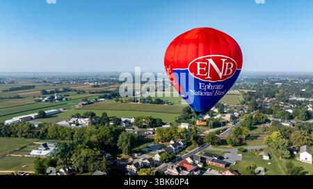 Bird in Hand, Pennsylvanie, le 14 septembre 2024 - Une montgolfière survole des champs verdoyants et des maisons confortables, capturant la beauté d'un ciel bleu clair. À proximité, les terres agricoles s'étendent au loin, améliorant la vue panoramique. Banque D'Images