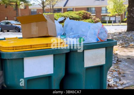 Les ordures sont empilées haut dans deux poubelles à l'extérieur d'un immeuble résidentiel le jour des travaux Banque D'Images
