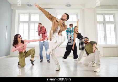Danseur homme et groupe de jeunes danseurs dansant activement à l'intérieur, bougeant et posant Banque D'Images
