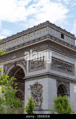 Vue en bas angle de l'Arc de Triomphe, montrant des pierres détaillées, des sculptures et des vues partielles des arches, contre un ciel bleu. Banque D'Images